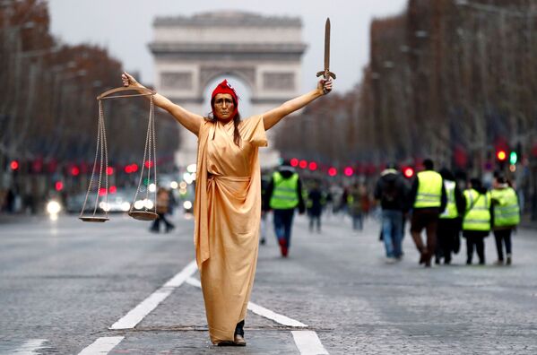 Женщина в костюме судьи и символа Французской Республики Марианна позирует во время демонстрации движения желтые жилеты на Елисейских Полях возле Триумфальной арки в Париже - Sputnik Узбекистан