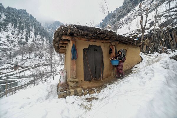 Индийская женщина рядом с сельским домом на окраине Сринагара в Кашмирской долине - Sputnik Узбекистан