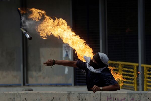 Демонстрант кидает бутылку с зажигательной смесью во время протестов против президента Гондураса Хуана Орландо Эрнандеса в Тегусигальпе - Sputnik Узбекистан