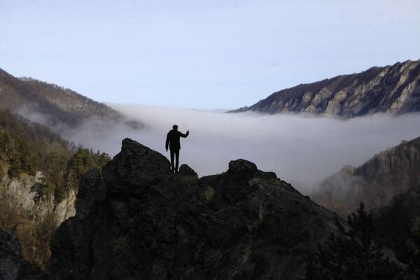 Турист фотографирует туман в ущелье горного склона Галанчожского района Чеченской республики - Sputnik Узбекистан