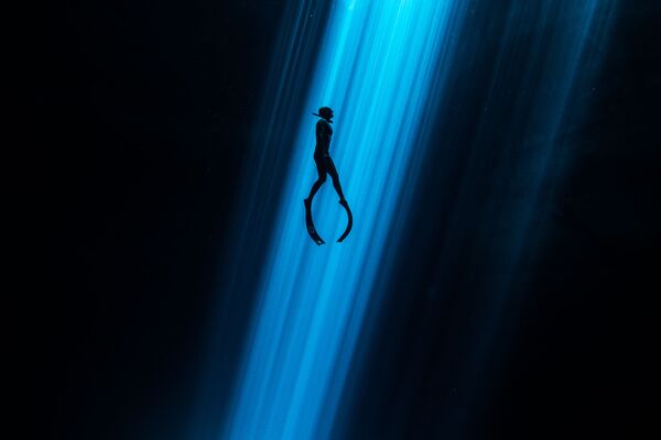Фридайвер, поднимающийся со дна сенота на снимке Light Beam, удостоившимся почетной награды в номинации Underwater Art конкурса 7th Annual Ocean Art Underwater Photo Contest - Sputnik Узбекистан