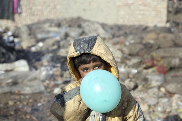 Афганский мальчик надувает воздушный шарик, окраина Кабула, Афганистан, 2017 год - Sputnik Ўзбекистон