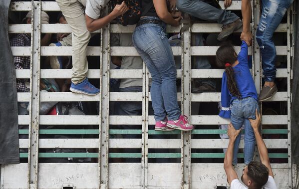 Венесуэльские мигранты лезут в грузовик на дороге из Кукуты в Памплону, Колумбия - Sputnik Узбекистан