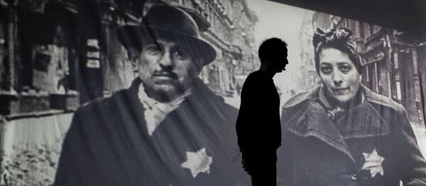 Мужчина на фоне фотографии, на которой изображены узники гетто Мужчина на фоне фотографии, на которой изображены узники гетто - Sputnik Узбекистан