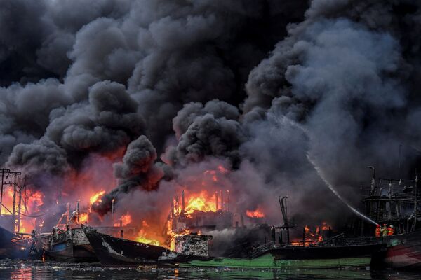Пожарные тушат горящие рыбацкие лодки в порту Муара Бару в Джакарте, Индонезия - Sputnik Узбекистан