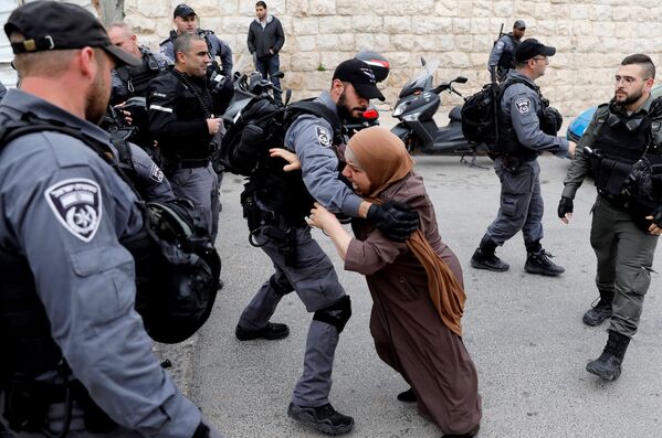 Палестинка пытается прорваться сквозь заслон израильских полицейских после того, как израильские власти закрыли вход на Храмовую гору в Иерусалиме - Sputnik Узбекистан