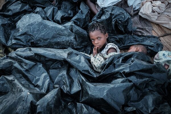 11-летняя Эния Хоакин Луис со своей 6-летней сестрой Луизой прячутся в укрытии из целлофана после разрушительного циклона в Мозамбике - Sputnik Узбекистан