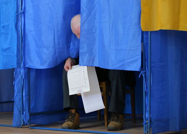 Мужчина изучает бюллетень в кабинке для голосования на президентских выборах на одном из избирательных участков Киева - Sputnik Узбекистан