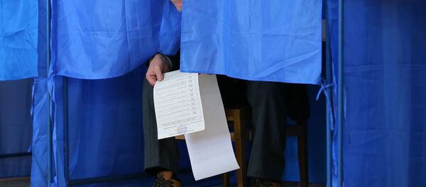 Мужчина изучает бюллетень в кабинке для голосования на президентских выборах на одном из избирательных участков Киева - Sputnik Узбекистан