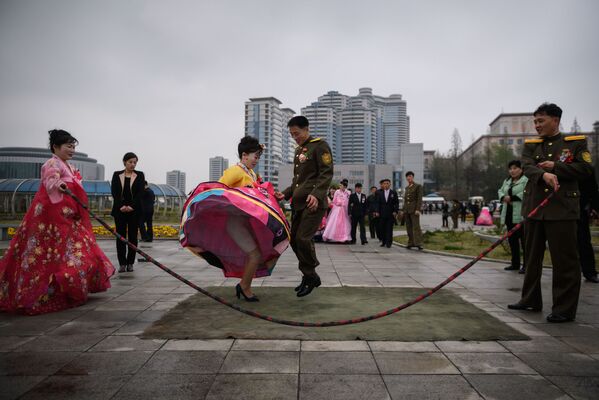 Новобрачные прыгают через скакалку во время свадебной фотосессии в Пхеньяне, Северная Корея - Sputnik Узбекистан