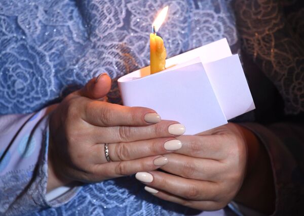 Свеча в руках верующей на праздничном пасхальном богослужении в храме Христа Спасителя в Москве. - Sputnik Узбекистан