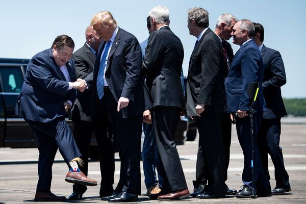 Вице-губернатор штата Луизиана Билли Нунгессер показывает президенту США Дональду Трампу носки с его изображением в аэропорте Лейк-Чарлз. - Sputnik Узбекистан
