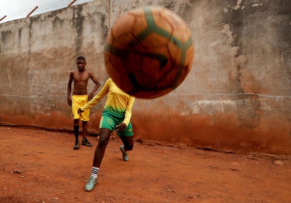  17-летняя Гаэль Дуле Ашери, входящая в первую группу девушек, которых тренируют профессиональные тренеры из Академии Rails Foot в Камеруне, играет в футбол с друзьями возле своего дома в Яунде - Sputnik Узбекистан