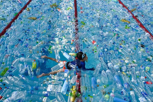 Ребенок плавает в бассейне, наполненном пластиковыми бутылками, во время информационной кампании, посвященной Всемирному дню океанов в Бангкоке, Таиланд. - Sputnik Узбекистан