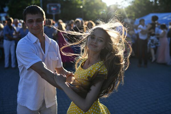 Молодые люди танцуют на общегородском балу на площади Нахимова в Севастополе. - Sputnik Узбекистан
