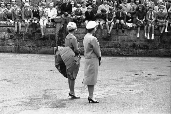 Ветер поднимает юбку принцессы Маргарет, пока они с королевой Елизаветой Второй ожидают прибытия президента США Дуайта Эйзенхауэра в замке Балморал, Шотландия. - Sputnik Узбекистан