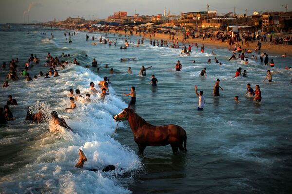 Люди купаются в водах Средиземного моря в жаркий день в северной части сектора Газа. - Sputnik Узбекистан