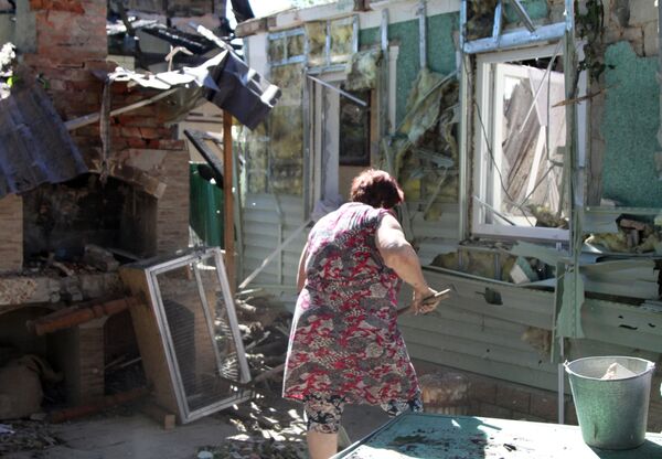 Женщина убирает мусор во дворе жилого дома в Донецке, пострадавшего в результате обстрела. - Sputnik Узбекистан