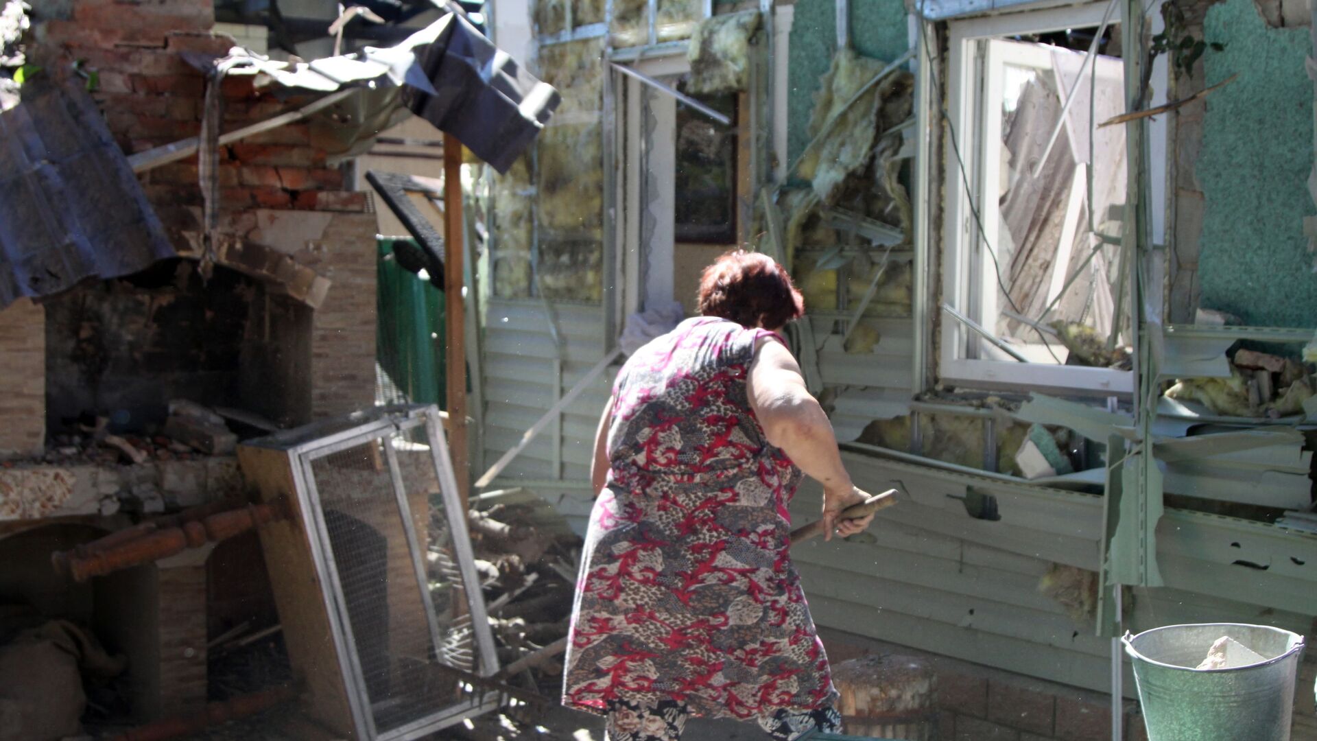 Женщина убирает мусор во дворе жилого дома в Донецке, пострадавшего в результате обстрела - Sputnik Ўзбекистон, 1920, 24.08.2021