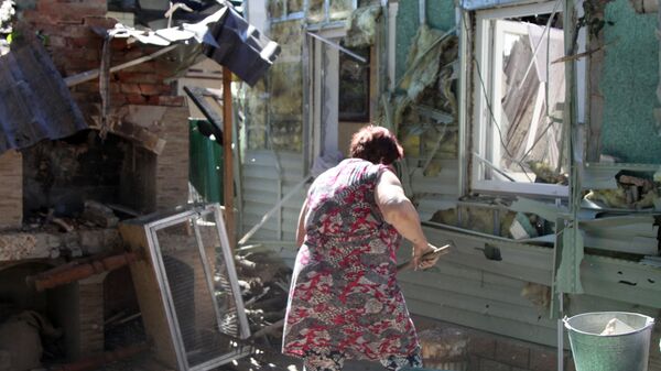 Женщина убирает мусор во дворе жилого дома в Донецке, пострадавшего в результате обстрела - Sputnik Ўзбекистон