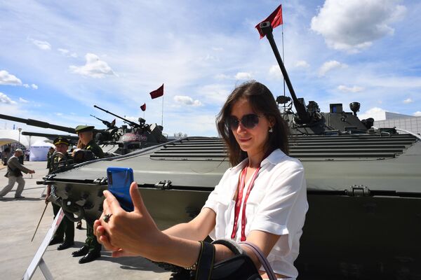 Посетительница фотографируется у боевой машины пехоты БМП-2 на Международном военно-техническом форуме Армия-2019 - Sputnik Узбекистан