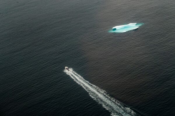 Катер проходит мимо айсберга в открытом океане возле Тасиилака, Гренландия - Sputnik Узбекистан