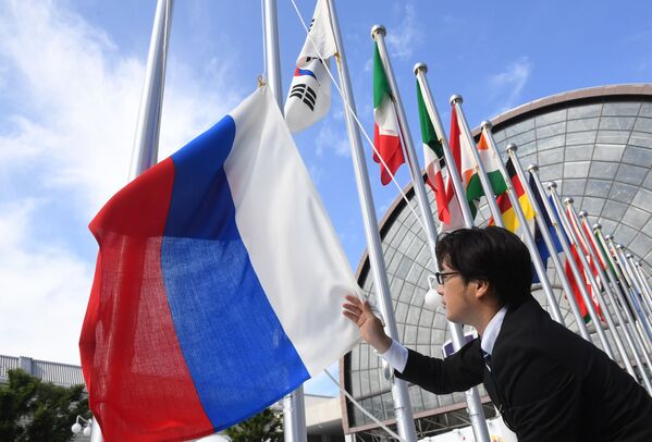Вывешивание флага России у международного выставочного центра INTEX Osaka перед открытием саммита Группы двадцати в японской Осаке - Sputnik Узбекистан