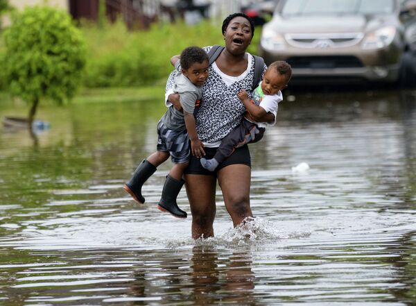 Мать несет на руках своих детей во время наводнения в Новом Орлеане  - Sputnik Узбекистан
