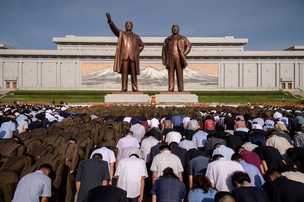 Жители Пхеньяна во время минуты молчания у памятника Ким Ир Сену и Ким Чен Иру в день отмечания 25-летия со дня смерти Ким ИМ Сена - Sputnik Узбекистан