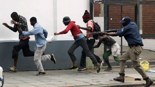Полицейский разгоняет демонстрантов на антимигрантском митинге в Претории, ЮАР. - Sputnik Узбекистан