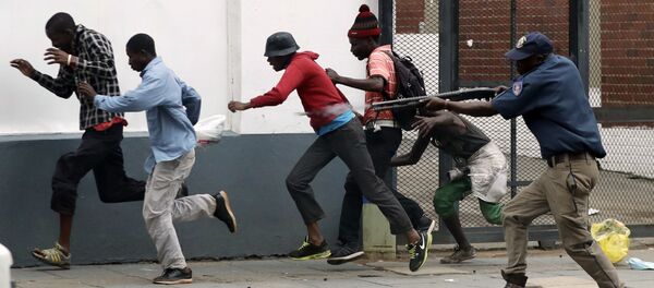 Полицейский разгоняет демонстрантов на антимигрантском митинге в Претории, ЮАР. - Sputnik Узбекистан