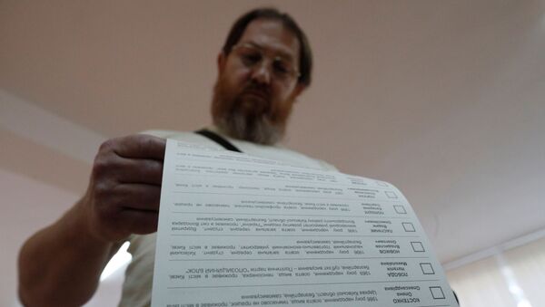 Мужчина смотрит бюллетень на избирательном участке  - Sputnik Узбекистан