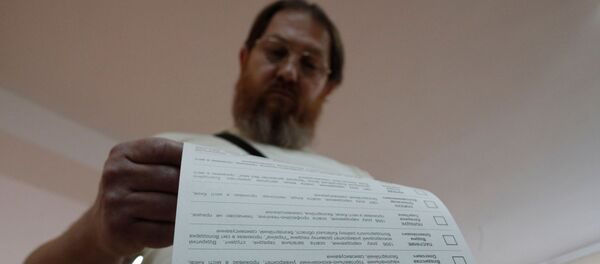 Мужчина смотрит бюллетень на избирательном участке  - Sputnik Узбекистан