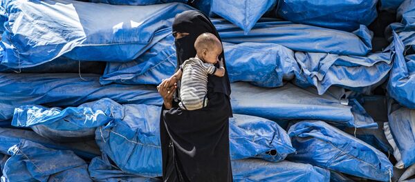 Женщина с никабе с ребенком на руках в лагере для перемещенных лиц al-Hol на северо-востоке Сирии - Sputnik Узбекистан
