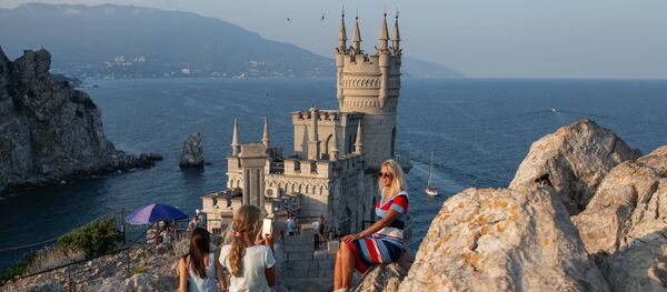 Otdixayushie fotografiruyutsya vozle zamka Lastochkino gnezdo na beregovoy skale v poselke Gaspra v Krimu Otdixayushie fotografiruyutsya vozle zamka Lastochkino gnezdo na beregovoy skale v poselke Gaspra v Krimu - Sputnik O‘zbekiston