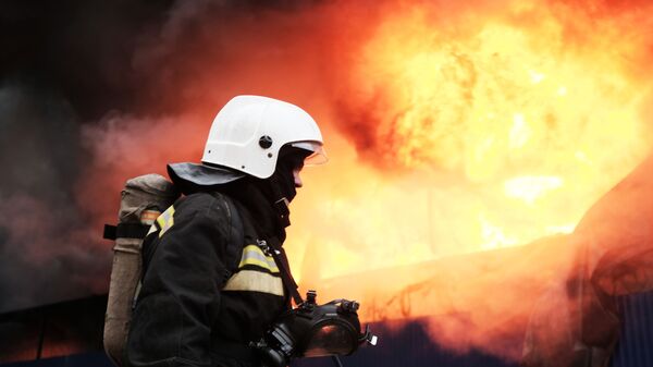 Сотрудник МЧС во время тушения пожара - Sputnik Узбекистан