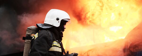 Сотрудник МЧС во время тушения пожара Сотрудник МЧС во время тушения пожара - Sputnik Ўзбекистон
