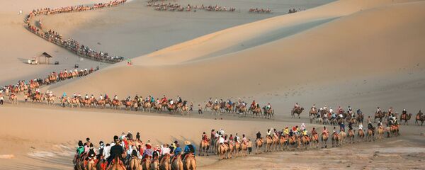 Туристы на верблюдах в пустыне в Дуньхуане, Китай Туристы на верблюдах в пустыне в Дуньхуане, Китай - Sputnik Ўзбекистон