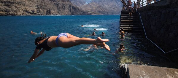 Купающиеся на плаже недалеко от деревни Агаэте на острове Гран-Канария, пострадавшей от лесного пожара Купающиеся на плаже недалеко от деревни Агаэте на острове Гран-Канария, пострадавшей от лесного пожара - Sputnik Ўзбекистон