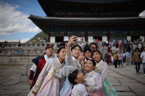 Одетые в традиционные корейские платья посетители фотографируются перед павильоном во дворце Кёнбоккун в Сеуле - Sputnik Узбекистан