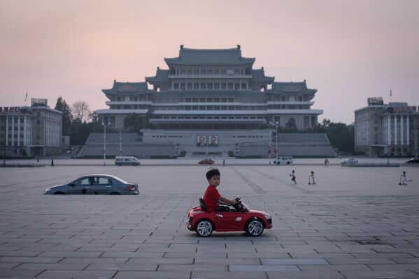 Мальчик на игрушечной машине на площади Ким Ир Сена в Пхеньяне, Северная Корея - Sputnik Узбекистан