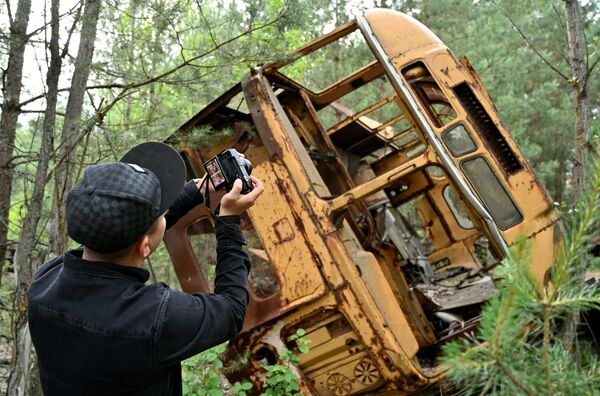Турист фотографирует автобус в зоне отчуждения Чернобыльской АЭС - Sputnik Узбекистан