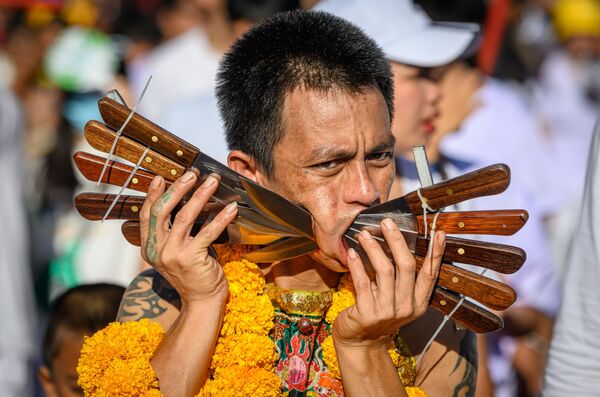 Участник фестиваля вегетарианства с пронизанными ножами щеками в Таиланде - Sputnik Узбекистан