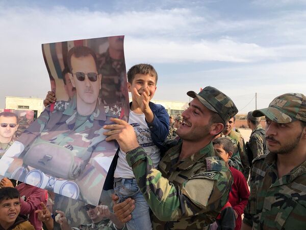 Дети и военнослужащие с плакатами с портретом президента Сирии Башара Асада в освобожденном сирийской правительственной армией городе Манбидж в Сирии - Sputnik Ўзбекистон
