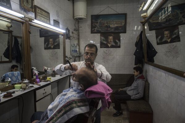 Парикмахер стрижет клиента в одной из парикмахерских в Дамаске - Sputnik Узбекистан