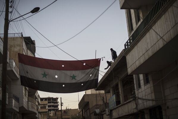Бойцы Соторо вывешивают флаг Сирии на одной из улиц в городе Камышли - Sputnik Узбекистан