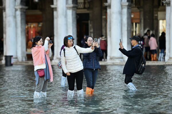 Туристы фотографируются на площади Сан-Марко во время наводнения в Венеции - Sputnik Узбекистан