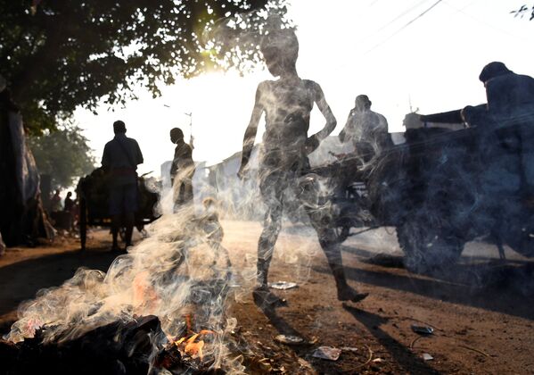 Люди проходят мимо горящего мусора в Калькутте, Индия - Sputnik Узбекистан