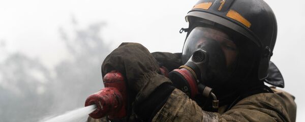 Сотрудник МЧС во время тушения пожара - Sputnik Ўзбекистон