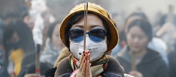 Jenshina v maske i solnsezashitnix ochkax vo vremya molitvi v perviy den Novogo goda v Pekine - Sputnik O‘zbekiston